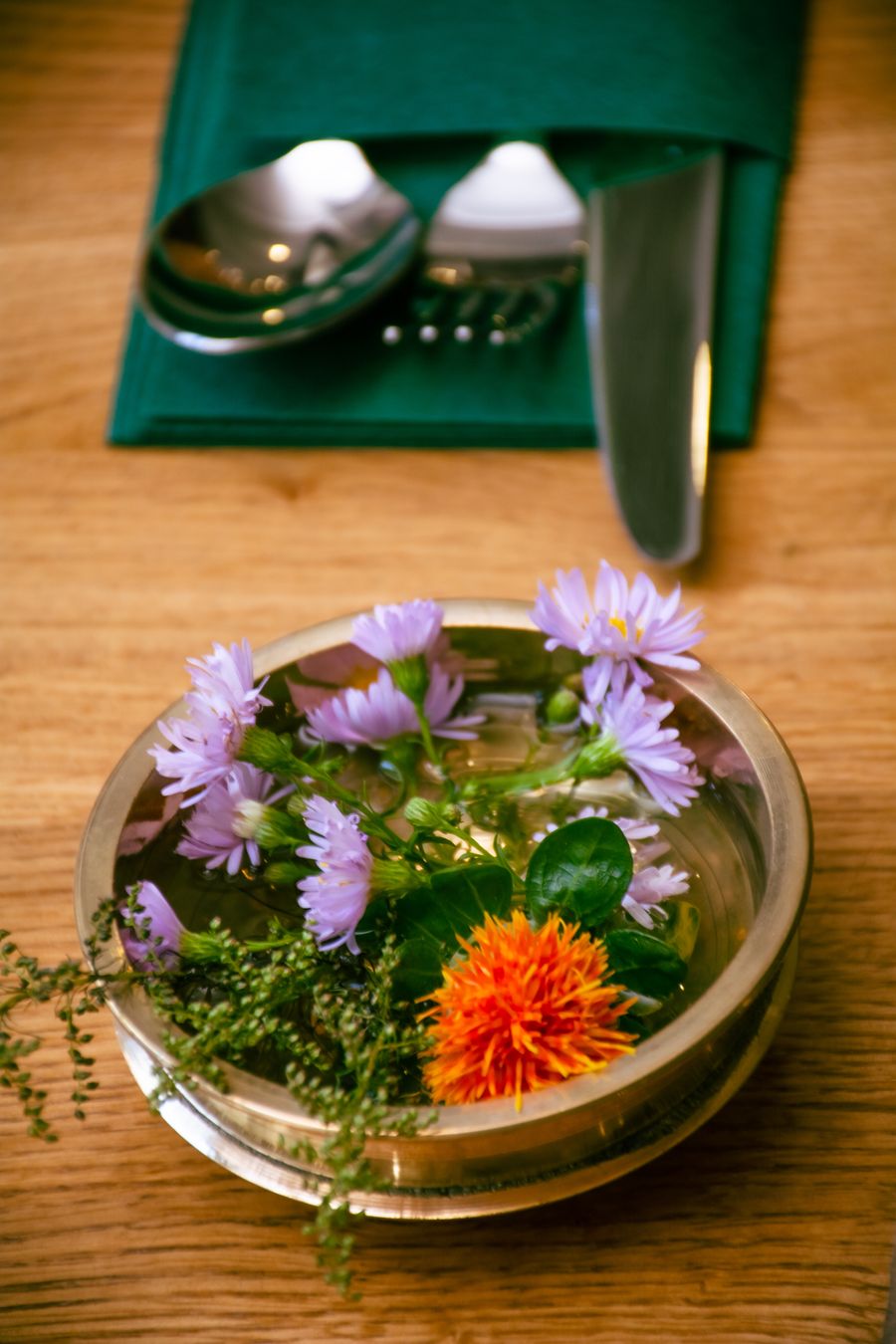 Messingschale mit Blumen und Besteck auf dem Tisch